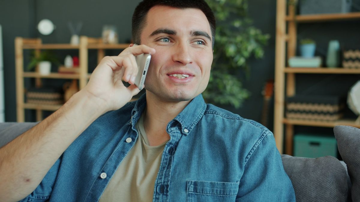 Mann snakker i mobiltelefonen hjemme i stuen
