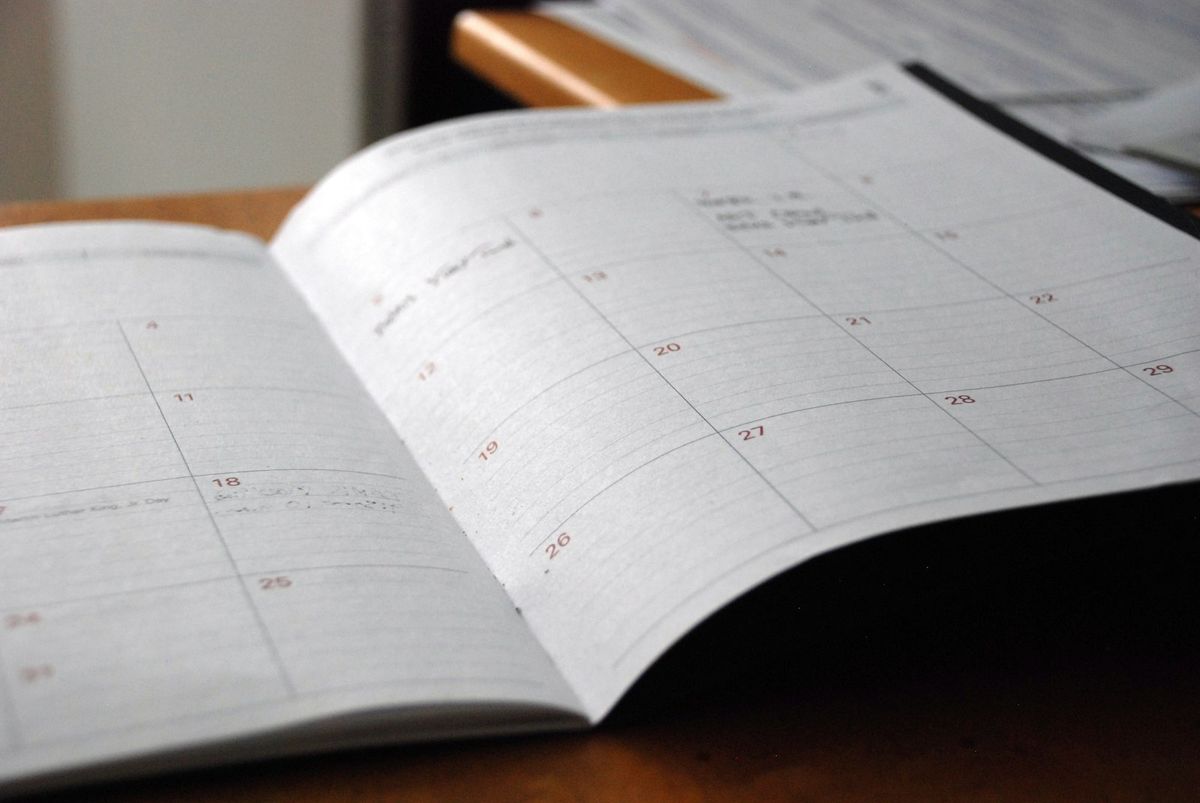 Åpen månedskalender og notatbok på et trebord